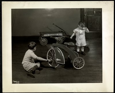 Two blind visually impaired boys playing with a tricycle and red wagon at the New York Association for the Blind, 111 East 59th Street, New York, 1937 by Byron Company